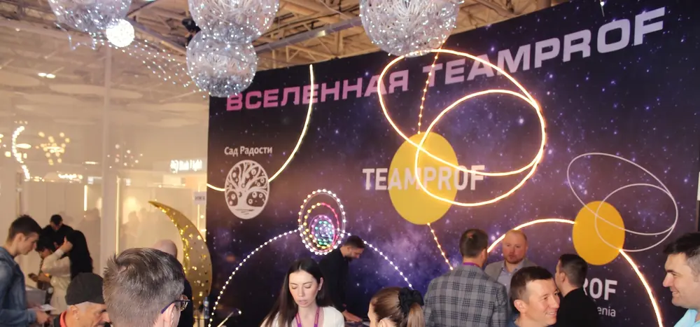Стенд TEAMPROF на Interlight Russia 2023: посетители у стойки, световые шары и гирлянды над стендом